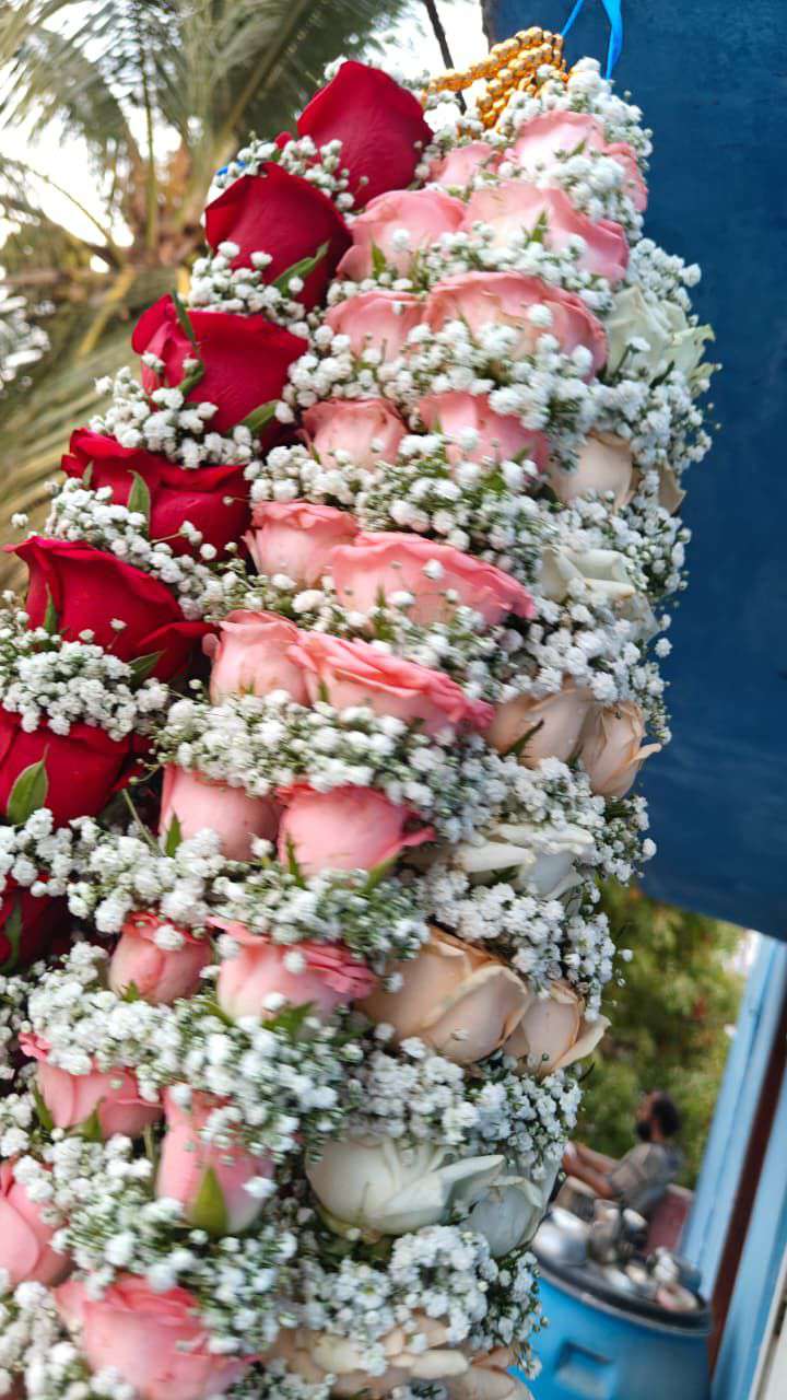 Close view of a garland of red, pink, peach and white roses with baby's breath.