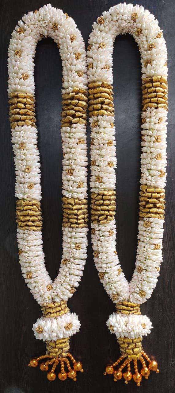 White garlands with gold-coloured bands and decorative tassels on a dark surface.