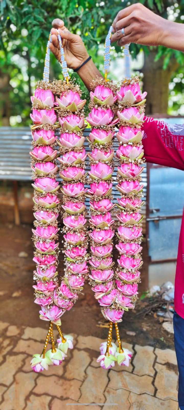 Hanging pink lotus-style garlands with green-edged floral units, fine filler bands and pale tassels.