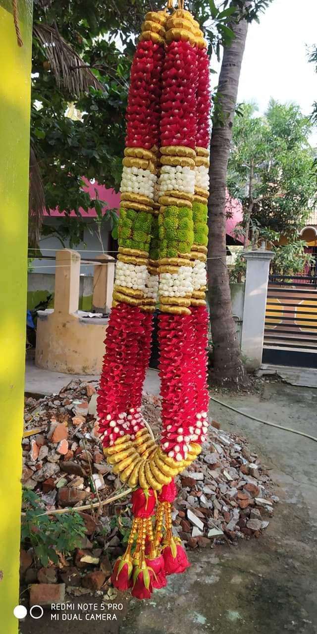 Red garland with green, white and gold colour blocks and red tassels, hanging outdoors.