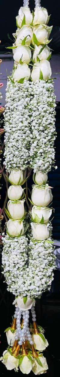 Garland alternating white rose sections and solid baby's breath blocks, with pearl and gold-cone tassels.