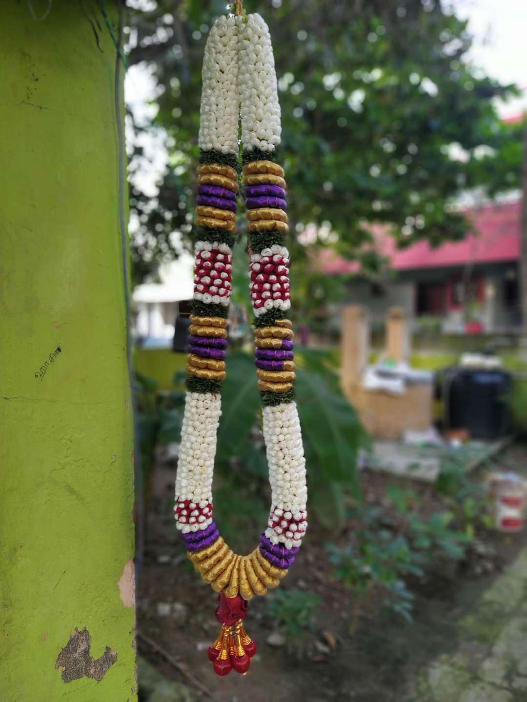 Single white garland with purple, gold and red-and-white bands, hanging outdoors.