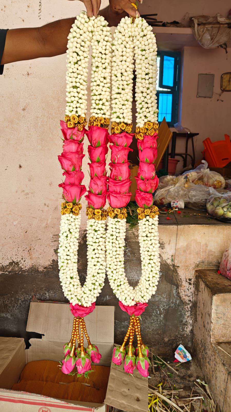 Pair of white tuberose garlands with a pink rose panel edged in gold, and pink rose tassels on gold beads.