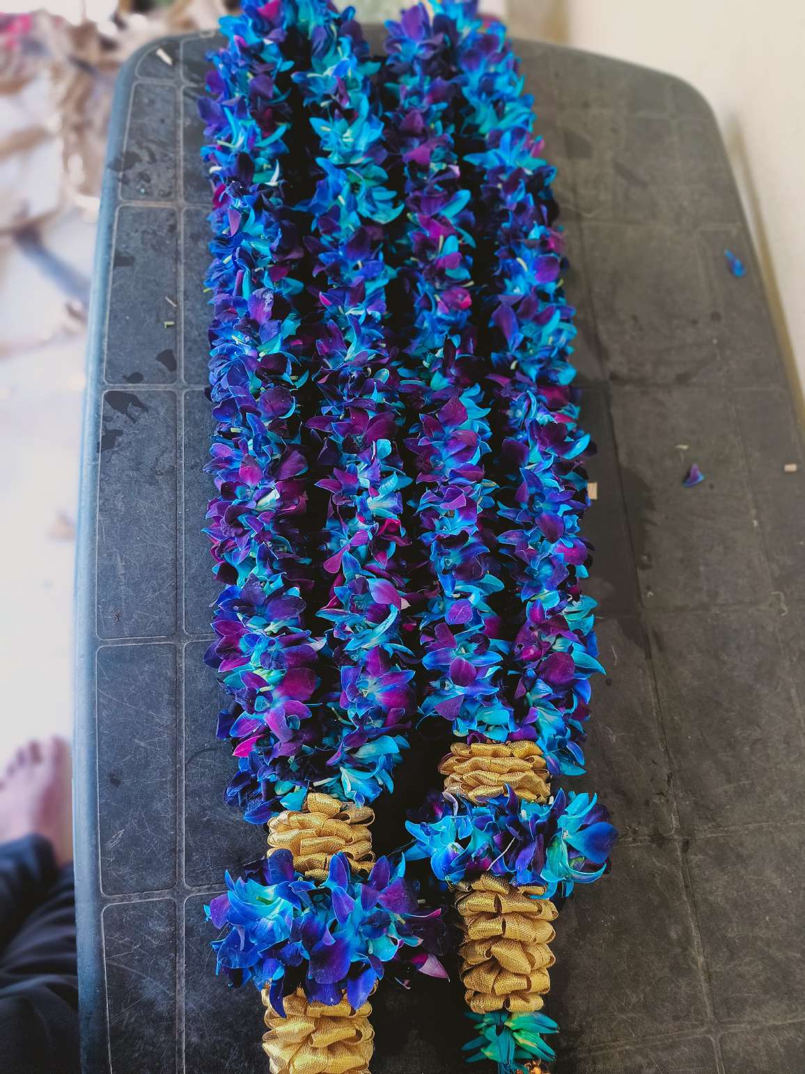 Pair of blue orchid garlands with gold bases, laid flat.