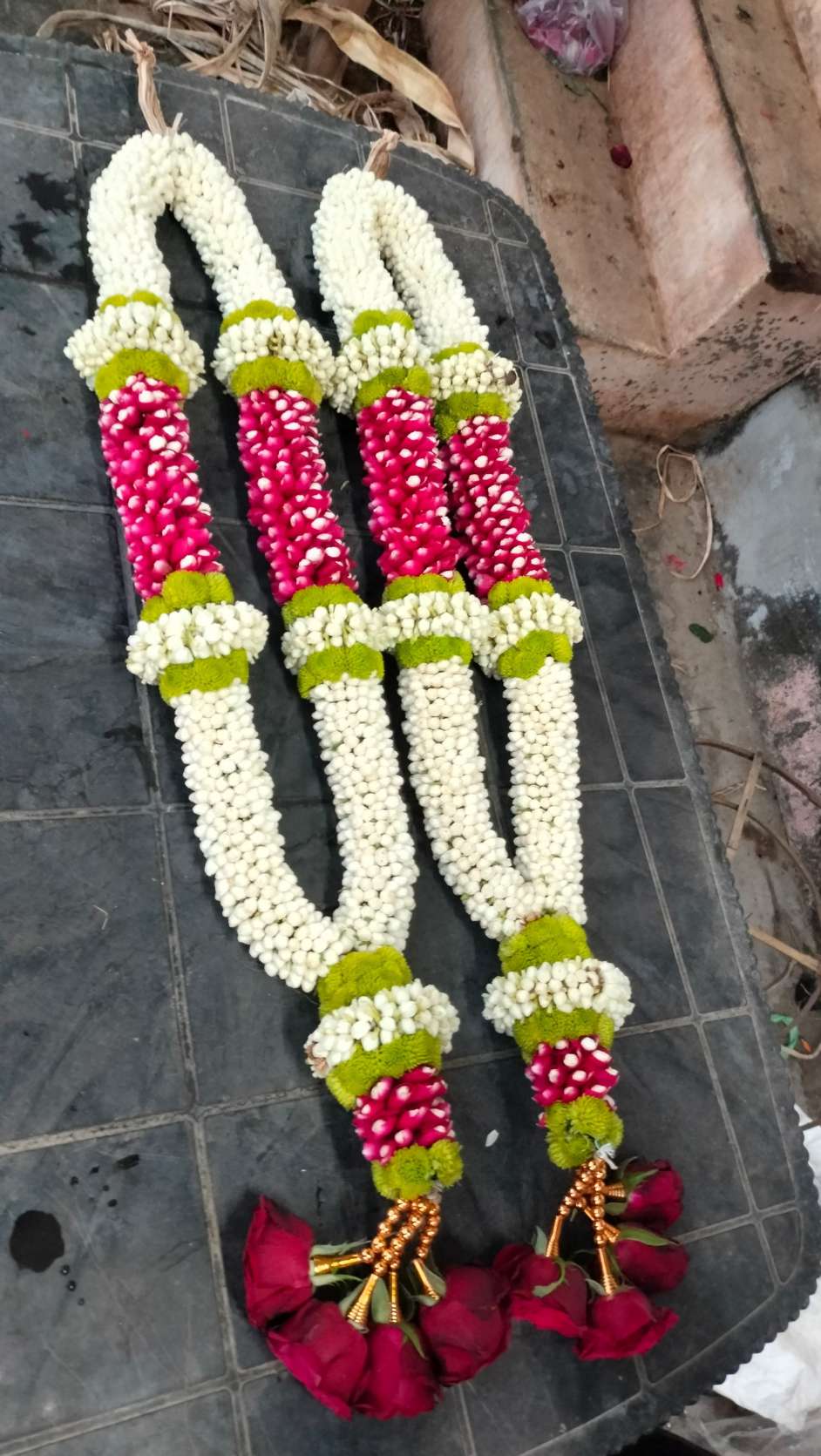 Pair of jasmine garlands with red bud panels framed by lime-green bands, and red rose tassels.