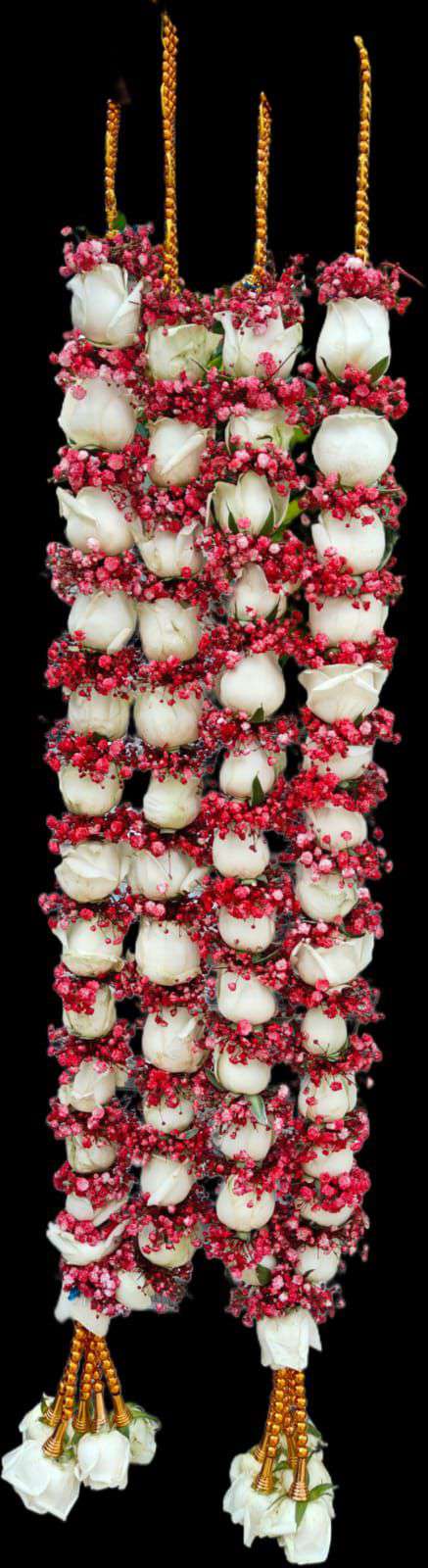 Pair of slim white rose garlands wrapped in red baby's breath, with gold hangers and white rose tassels, on a black background.