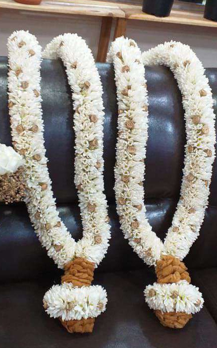 Pair of ivory floral garlands with gold-wrapped bases, displayed on a sofa.