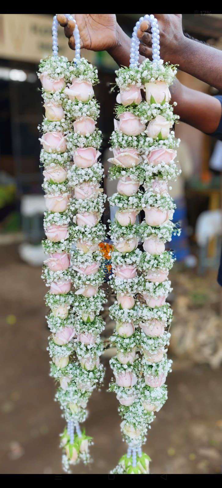 Pair of pale pink rose garlands with baby's breath and green accents, pearl hangers and small tassels.
