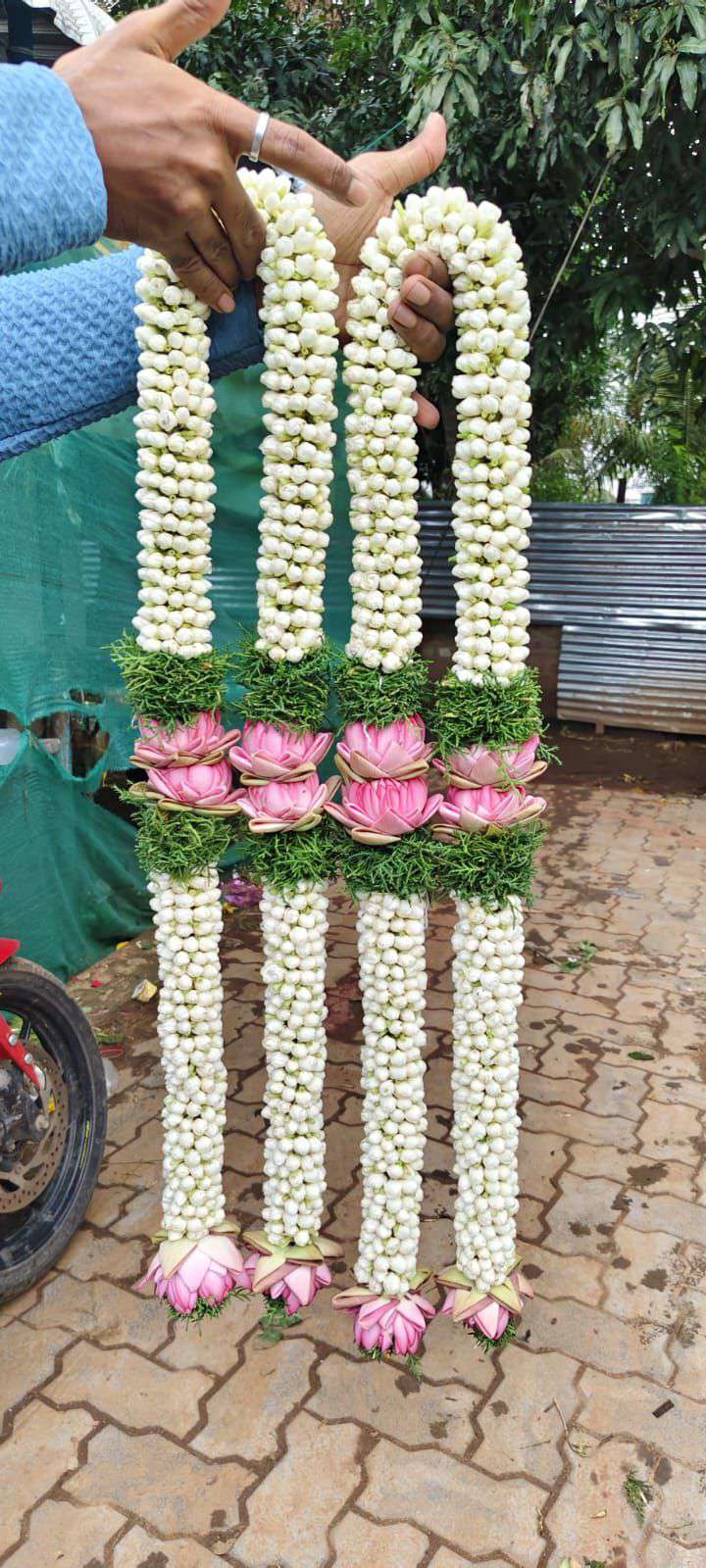 White bud garlands with pink lotus-style flowers in the centre, green separators and pink tassels.