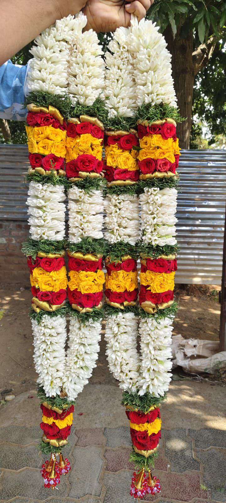 Dense white garlands with red and yellow floral panels, green separators and decorated tassels.