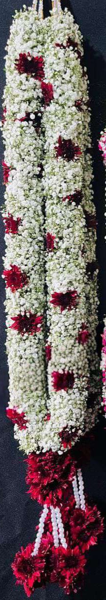 Baby's breath garland with maroon chrysanthemum accents and maroon tassels.