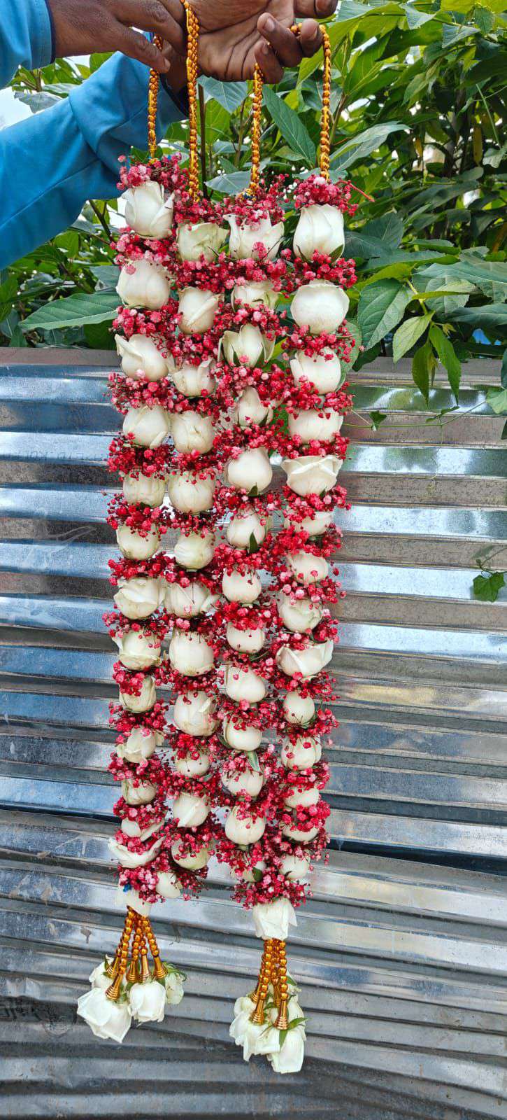 Pair of white rose garlands wrapped in red baby's breath, with gold bead hangers and white rose tassels.