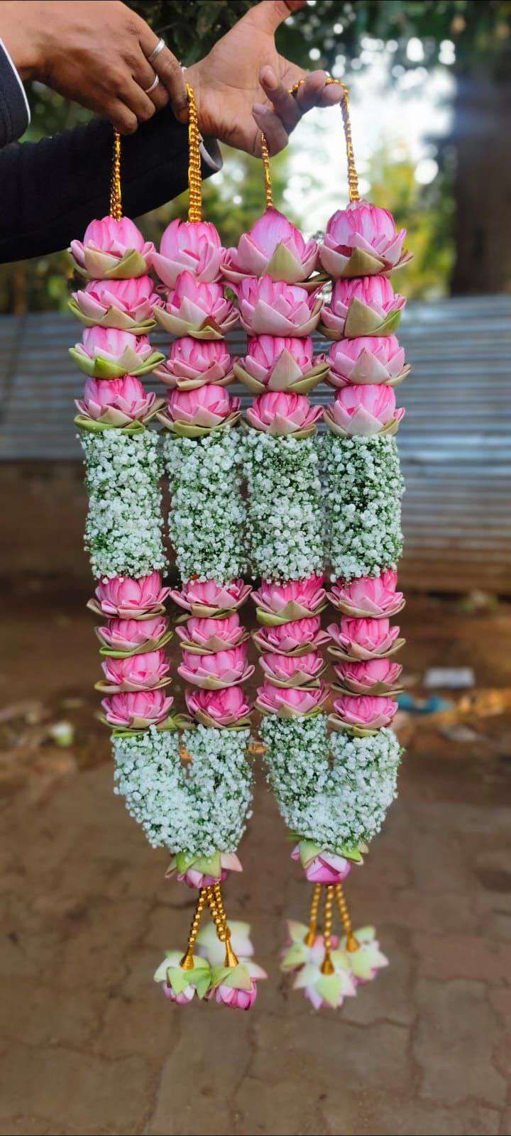 Pink lotus-style garlands with broad white floral panels and matching pink tassels.
