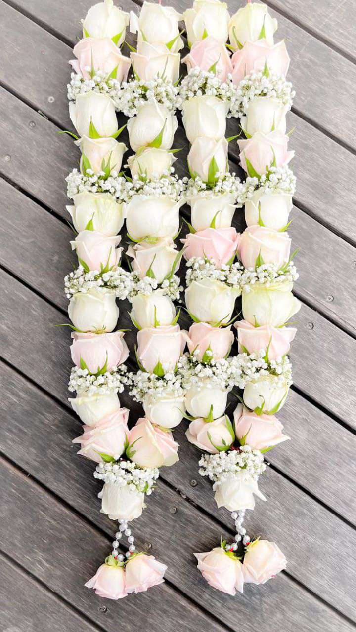 Ivory and pale pink rose garlands arranged on wooden boards, with fine white floral bands and pale rose tassels.