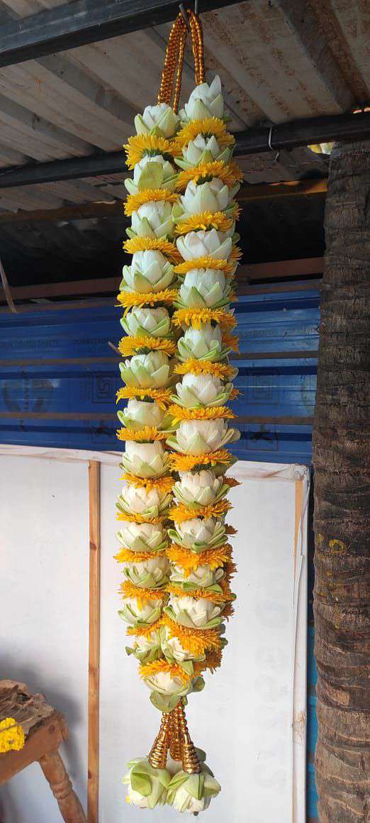 A hanging ivory floral garland with yellow flower bands and pale tassels.