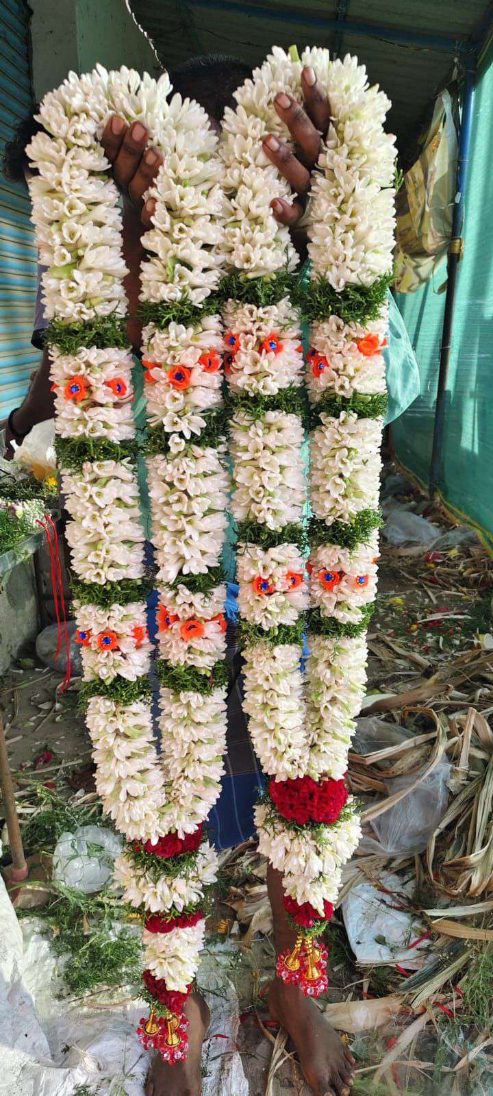 Pair of tuberose garlands with green bands and small coral flower accents.