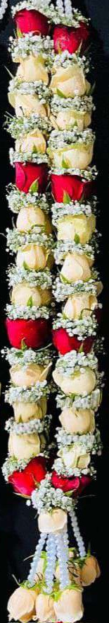 Garland of cream roses with occasional red roses and baby's breath, pearl hangers and cream rose tassels.
