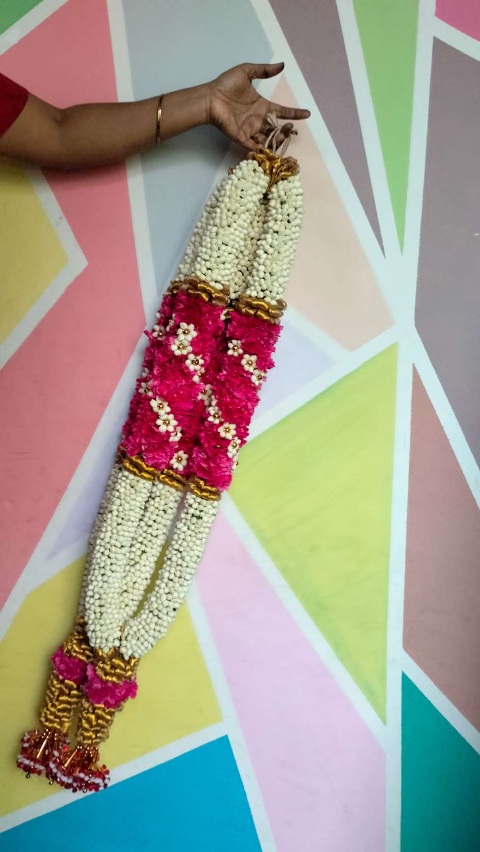 Ivory garland with a red rose panel edged in gold, held against a painted wall.