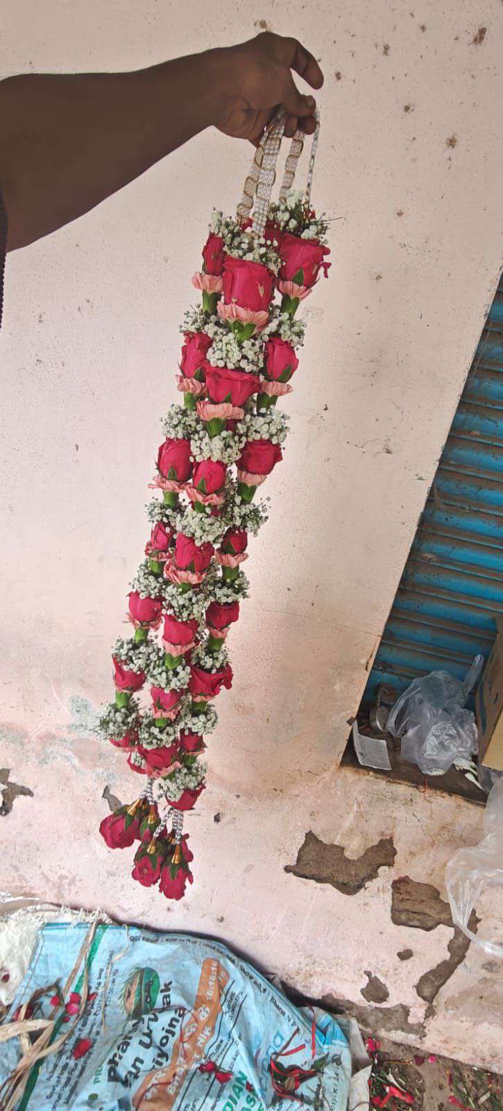 Single slim garland of rose-pink and red roses with baby's breath and red rose tassels.