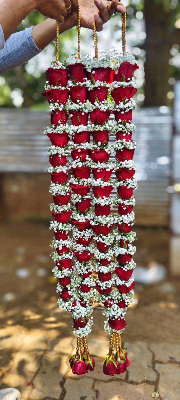 Pair of red rose garlands in rows divided by thick baby's breath bands, with gold bead tassels.