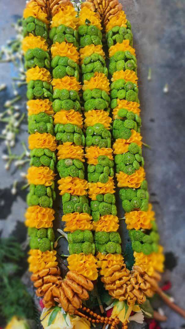 Garlands banded in yellow and green chrysanthemums with gold bases, laid flat.