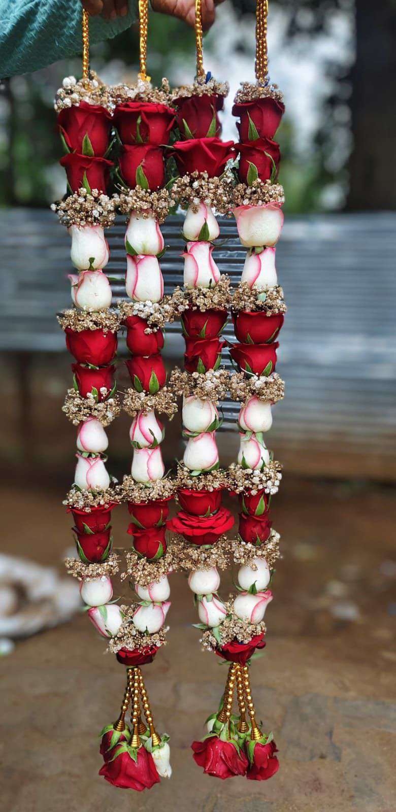 Pair of garlands alternating red and white roses between bands of golden-toned baby's breath, with red rose tassels.