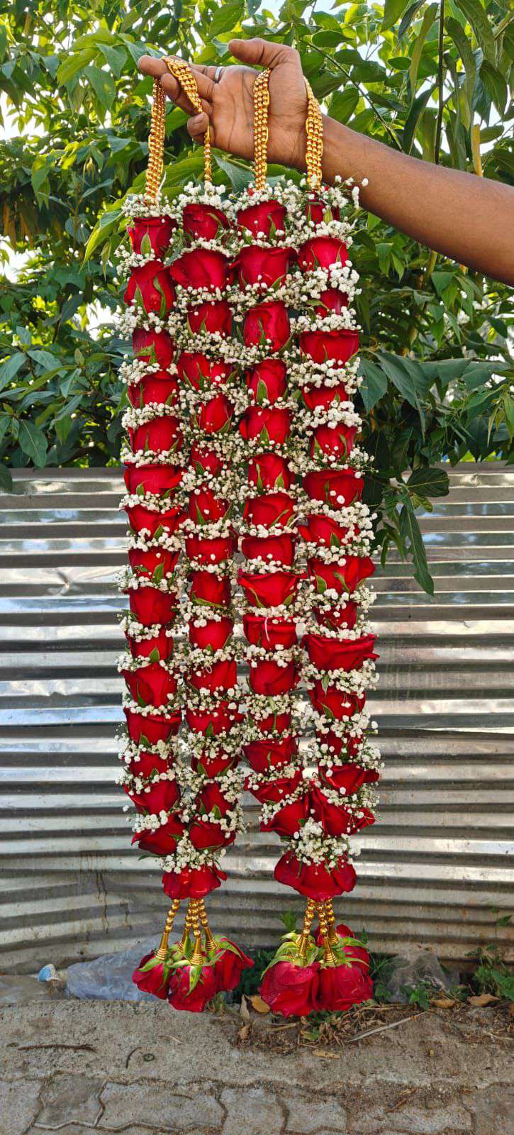 Pair of dense red rose and baby's breath garlands with gold bead hangers and red rose tassels.