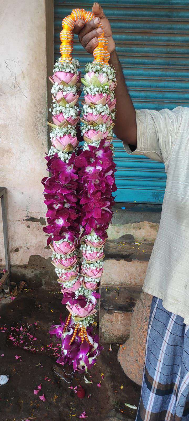 Garland of pink lotus with baby's breath and a purple orchid section, on an orange bead hanger.