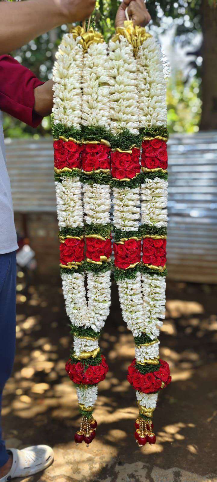 Pair of tuberose garlands with red rose panels edged in green and red rose tassel balls.