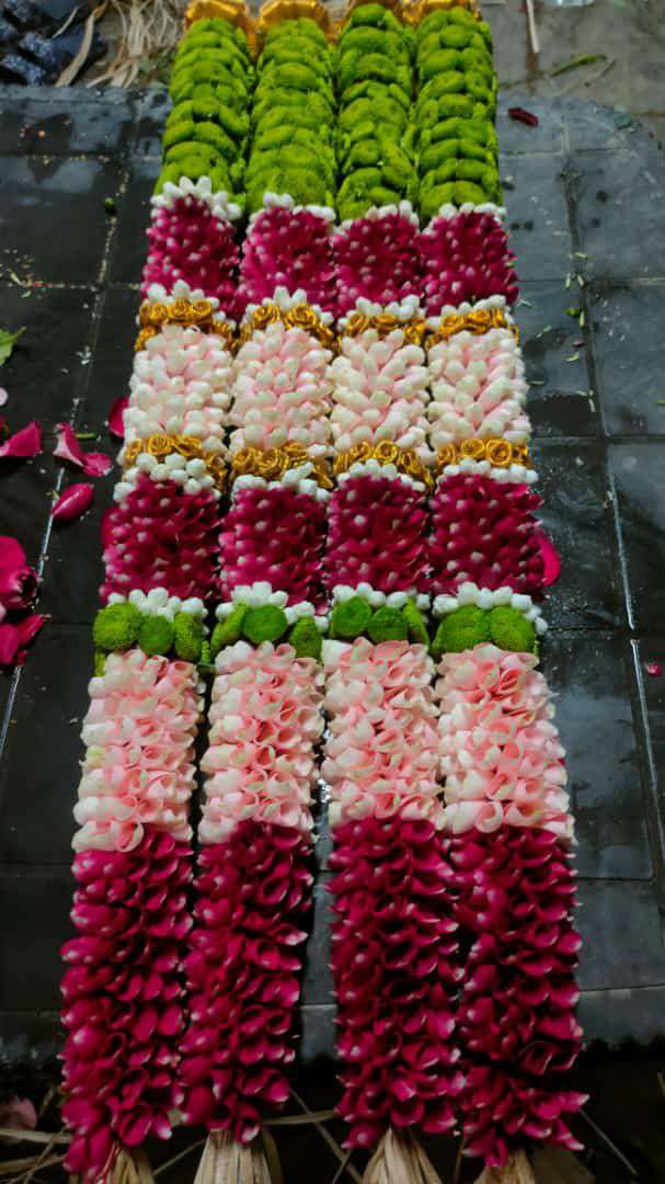 Garland in blocks of red, pink, white and green rose petals, laid flat.