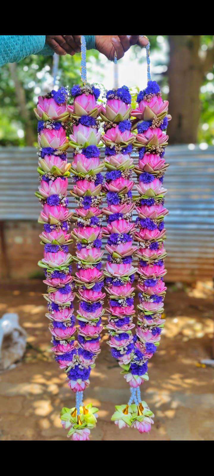Pink lotus-style garlands with purple floral accents and pale flower tassels.