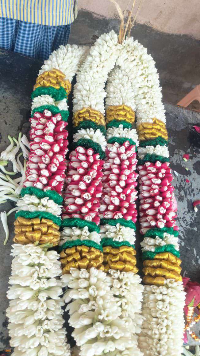 Tuberose garland with red bud panels framed by gold and green bands, laid flat.