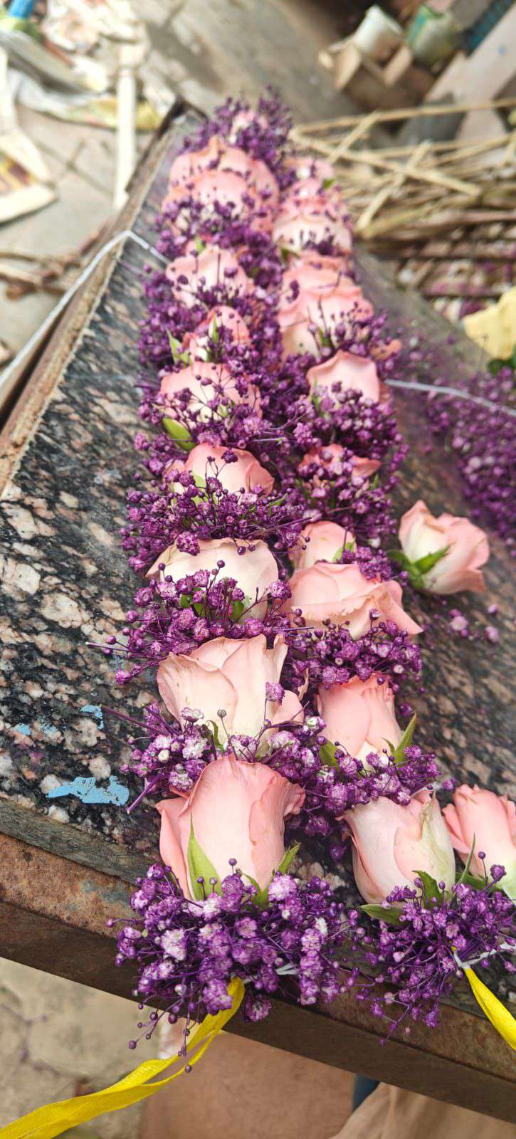 Peach roses set in purple baby's breath, laid along a stone surface.