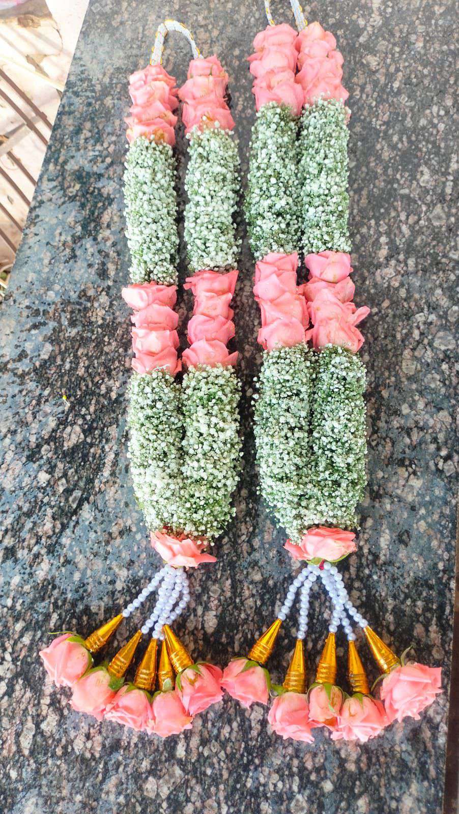 Pair of garlands with peach rose sections between thick baby's breath sections, pearl strands and gold-cone rose tassels.