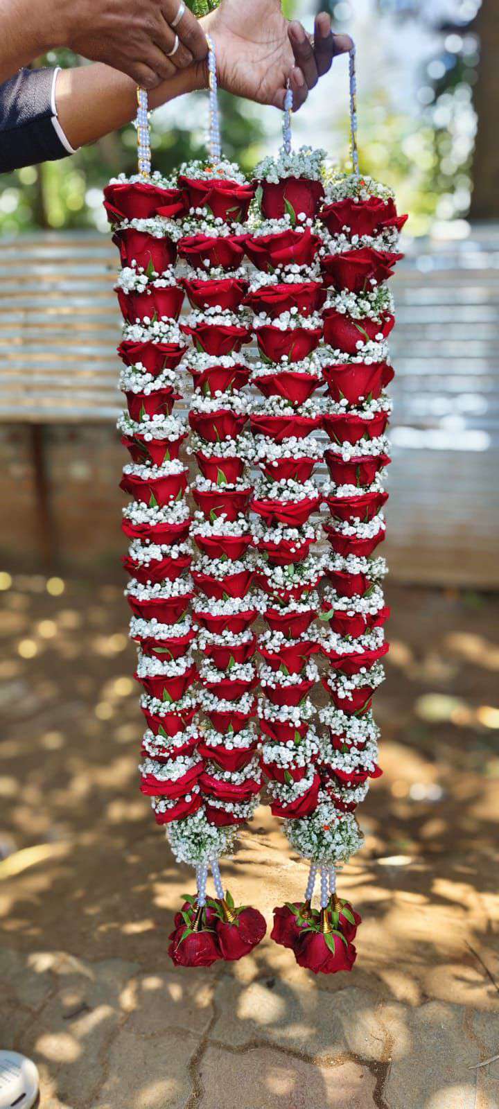 Pair of red rose garlands with baby's breath rings, white pearl hangers and red rose tassels.