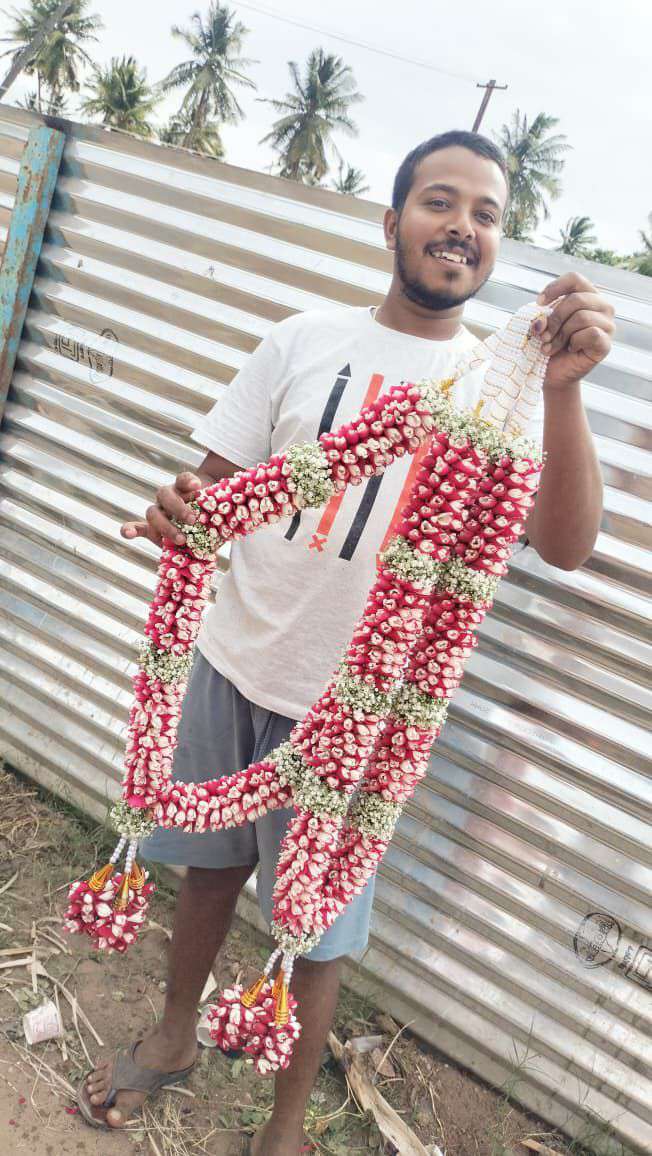 Red-and-white bud garland with baby's breath bands and bud tassels, held up by a man.
