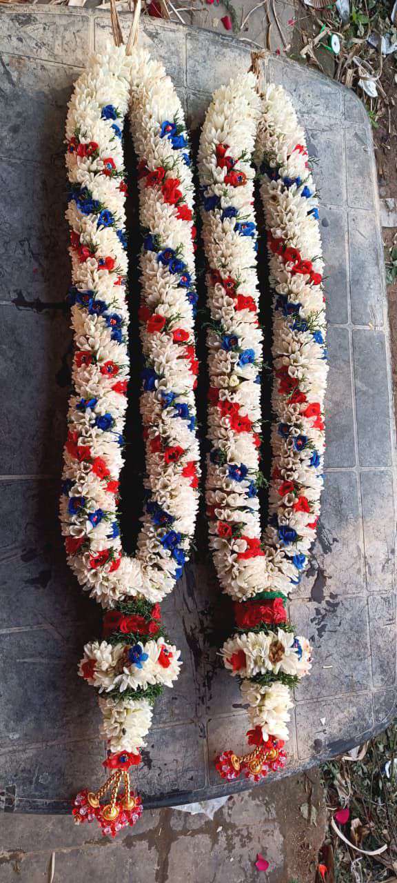 Pair of tuberose garlands with blue and red diagonal accents and red tassels, laid flat.