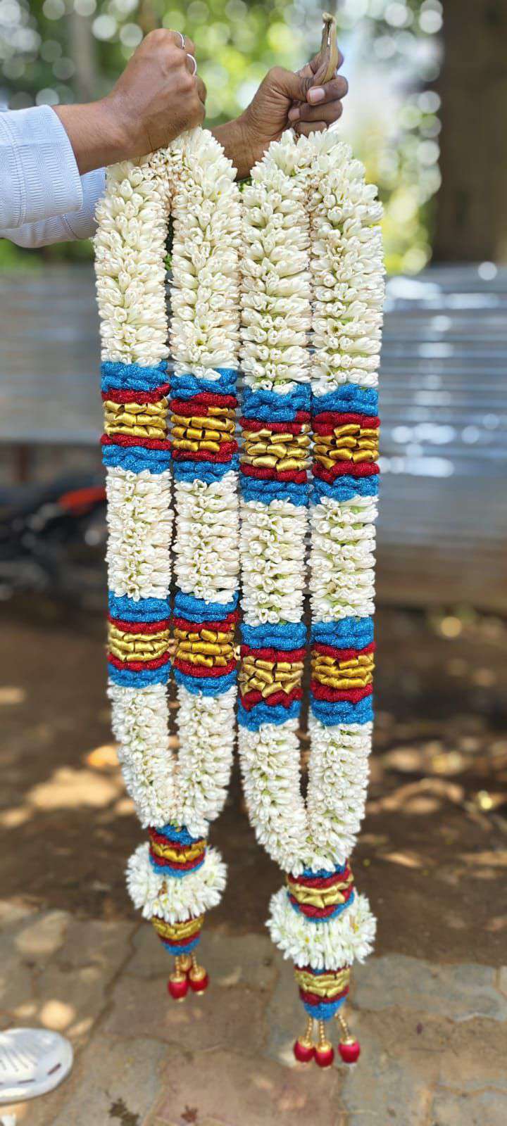 Pair of tuberose garlands with blue, red and gold bands and blue-and-red tassels.