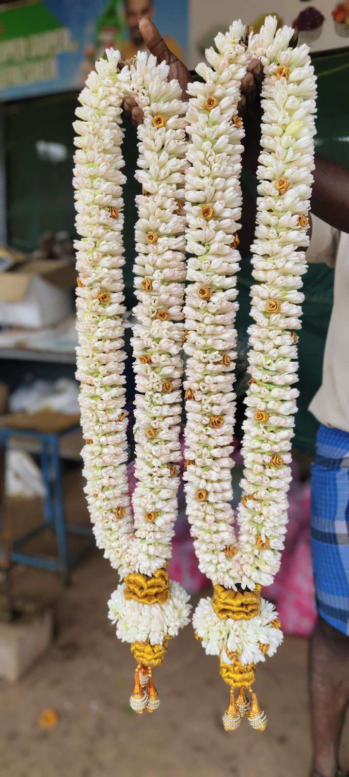 Pair of white tuberose garlands dotted with gold accents, with gold and white tassels.