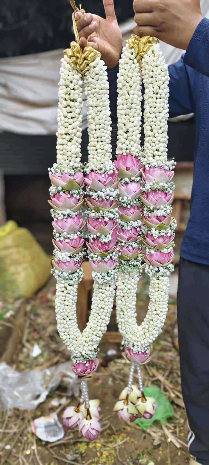 Pair of jasmine garlands with a band of pink lotus and baby's breath, gold tops and lotus tassels.