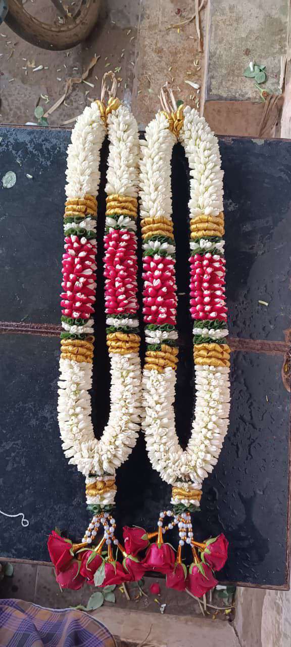 Pair of tuberose garlands with a red bud panel framed by gold and green bands, and red rose tassels.