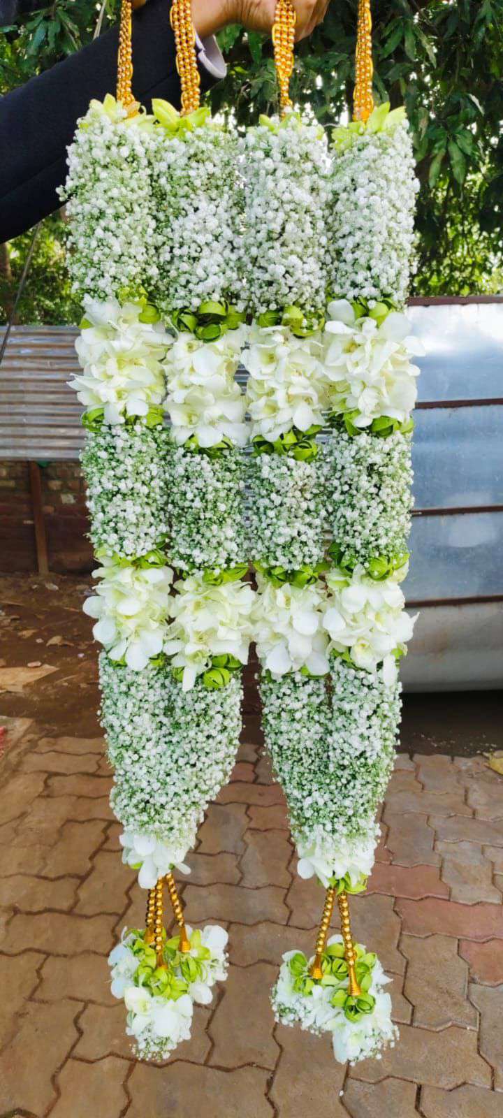 White floral garlands with broad open-flower bands, green accents and pale tassels.