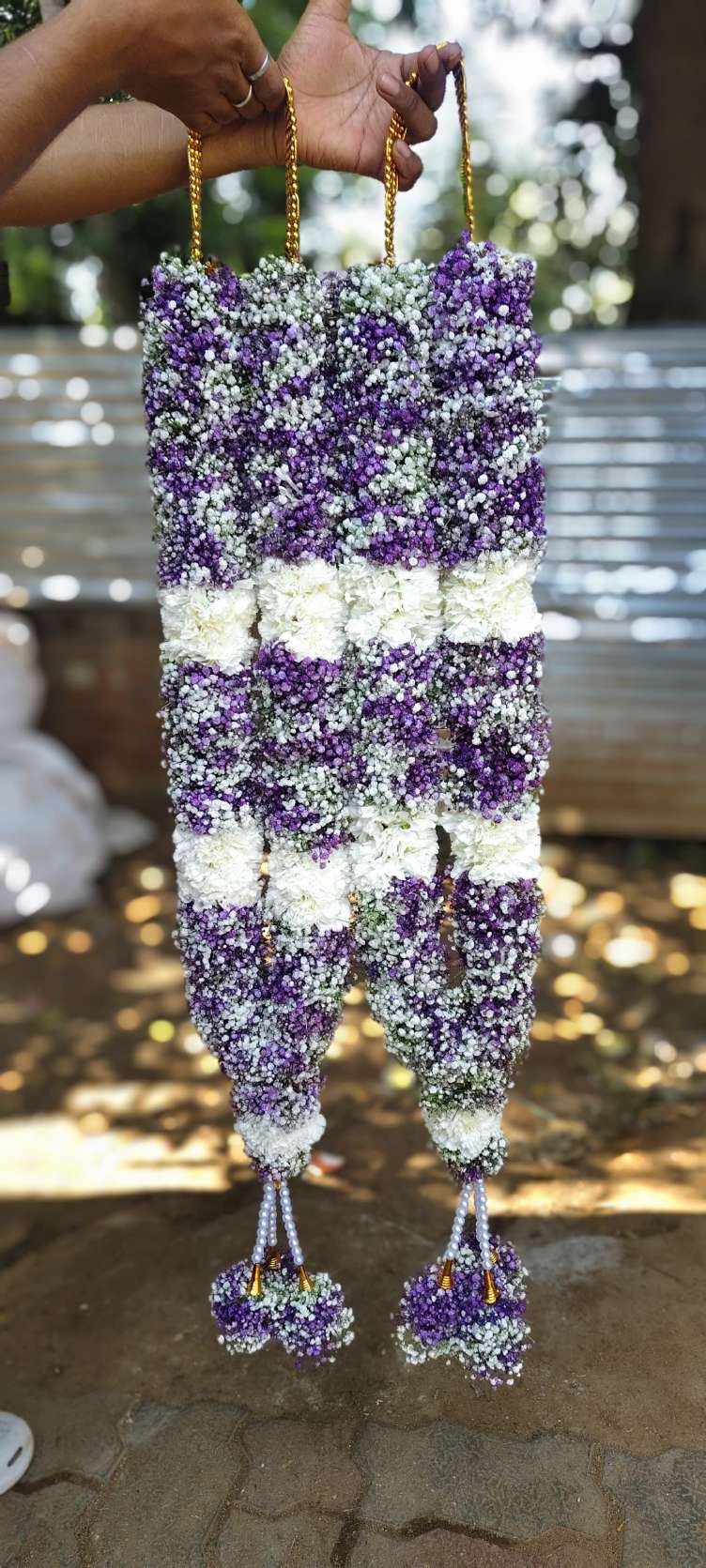 Dense purple and white floral garlands with broad white bands and rounded floral tassels.