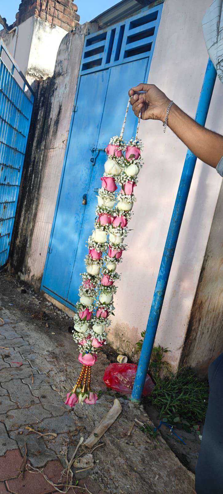 Single slim pink and white rose garland hanging beside a blue door.