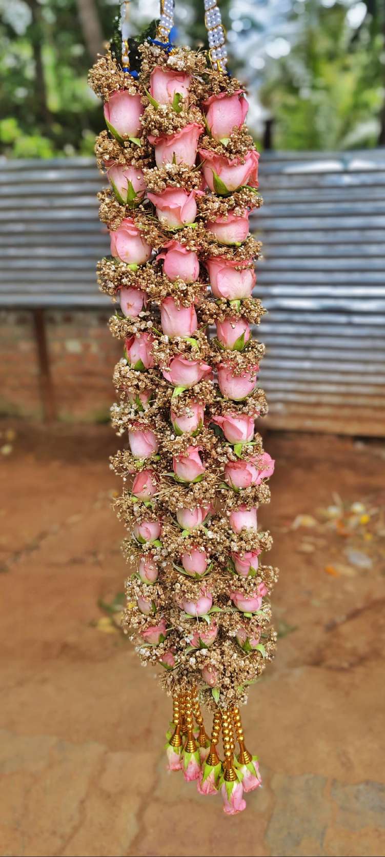 Pink rose garland wrapped in golden-toned baby's breath, with gold bead hangers and pink rose tassels.