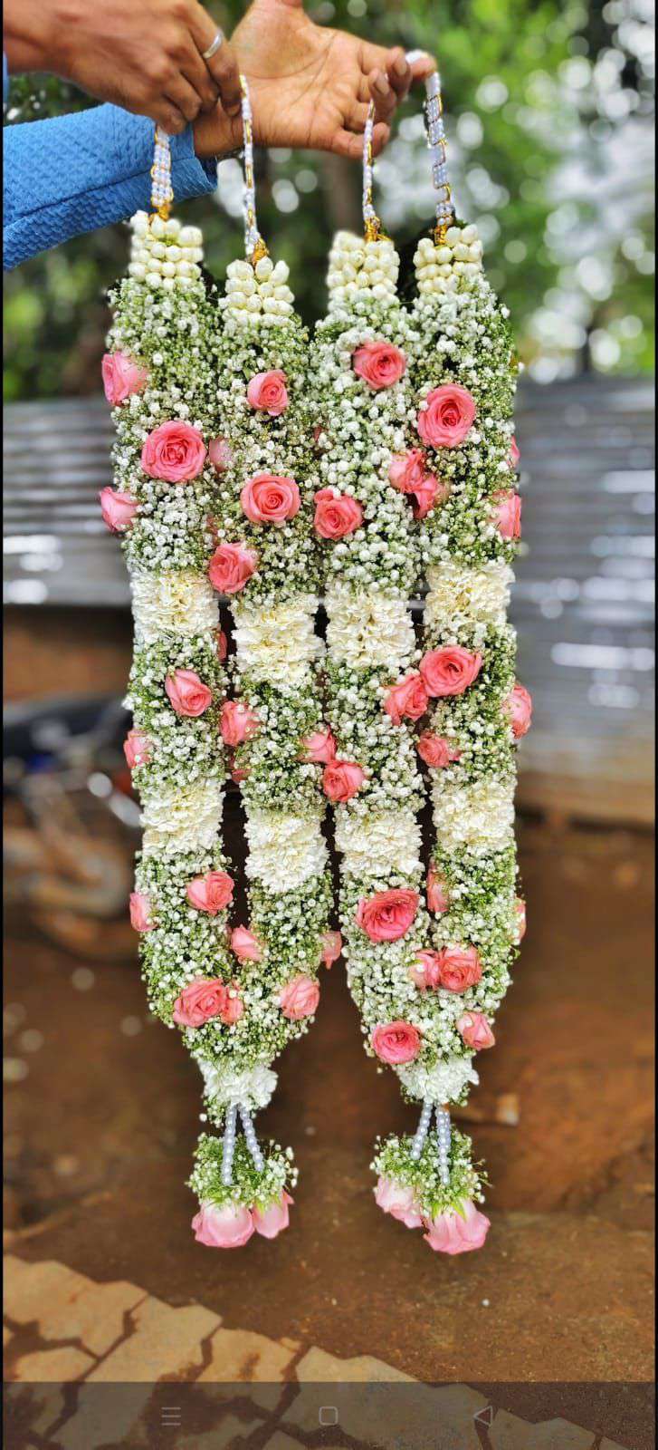 Dense white garlands with small pink rose accents, white bud clusters and pink tassels.