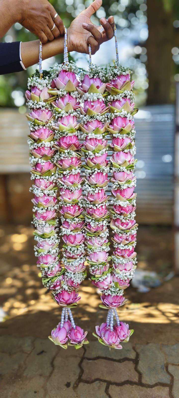 Pair of open pink lotus garlands with baby's breath, white pearl hangers and small lotus tassels.