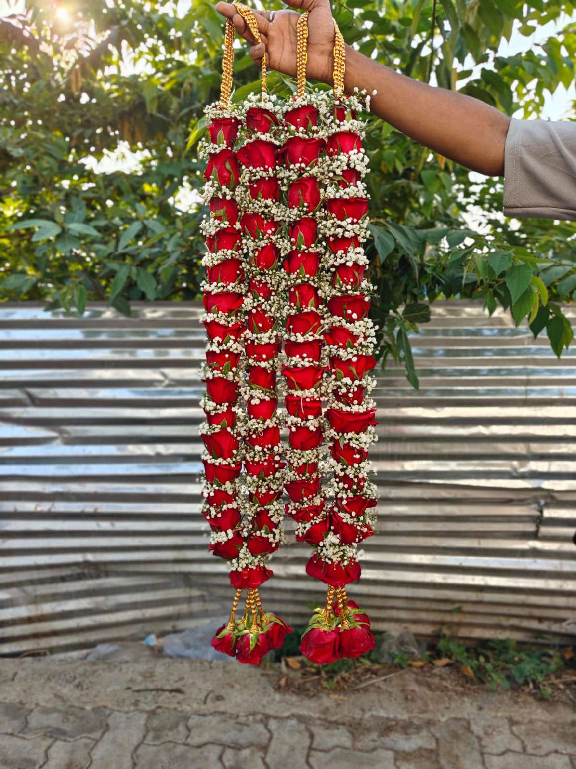 Pair of slim red rose and baby's breath garlands with gold bead hangers and red rose tassels.