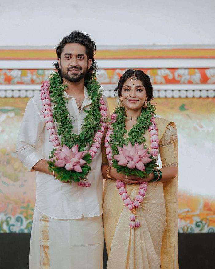 Pink lotus and green leaf garlands with a large lotus pendant, worn by a couple.